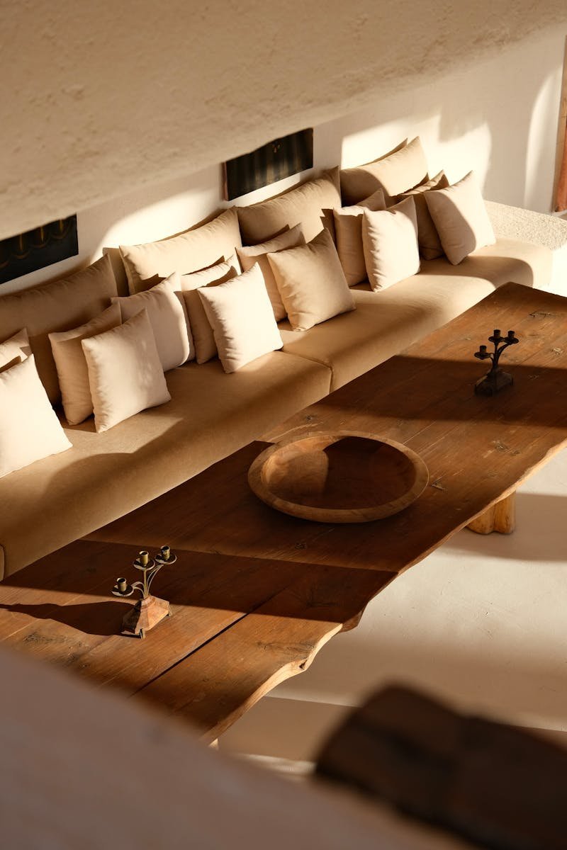 Warm, inviting Moroccan interior featuring a rustic wooden table and beige cushions in natural sunlight.